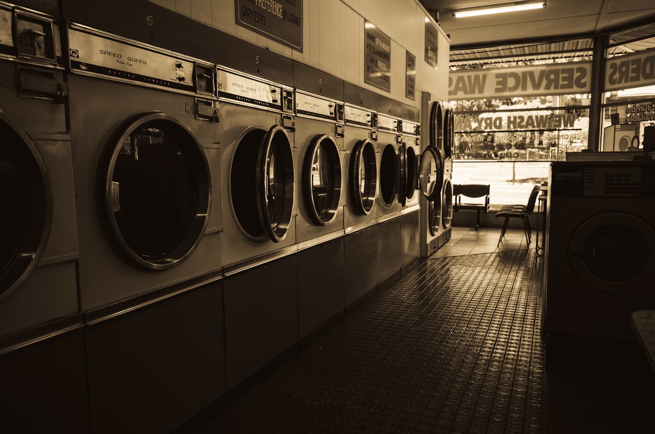 Sepia-toned image of a laundromat interior showcasing a row of classic washing machines.