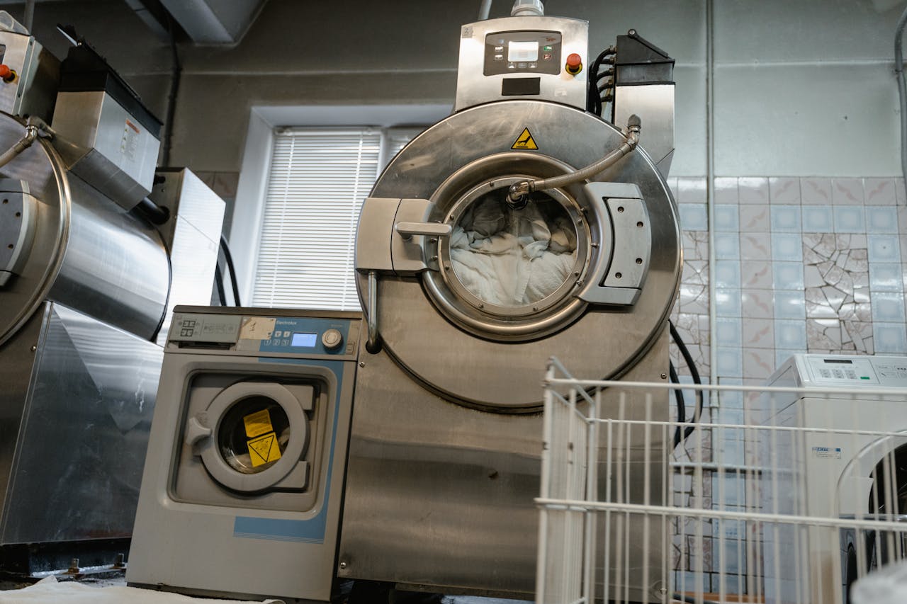 Large industrial laundry machines in a service room environment.